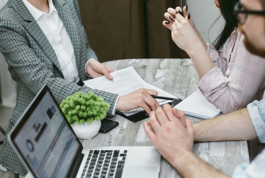 Professionelles Meeting zur Besprechung von Geschäftsvereinbarungen, Laptops und Dokumente liegen auf einem rustikalen Tisch.